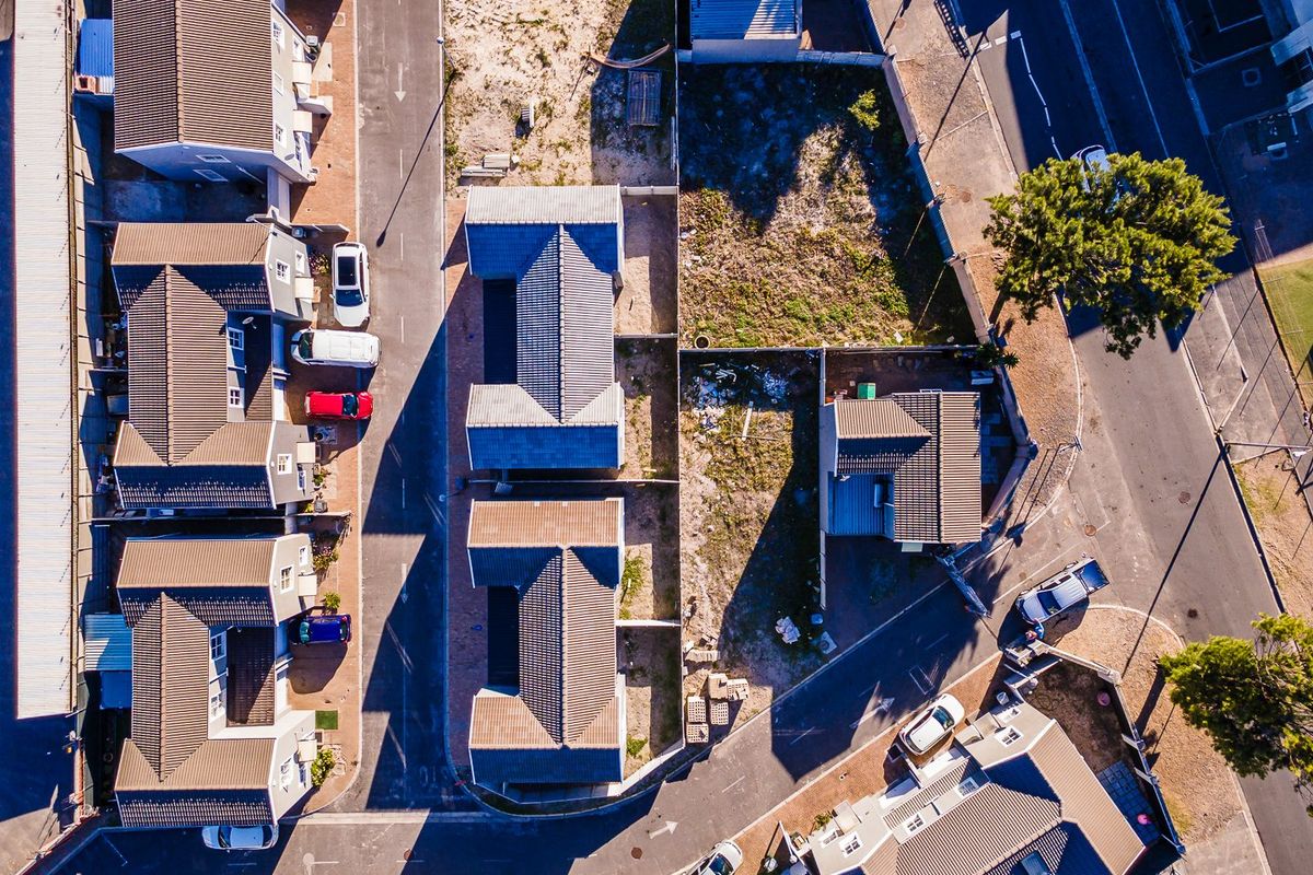 An aerial view of a residential housing complex showing the layout of multiple units, tiled roofs, and surrounding paved access roads.