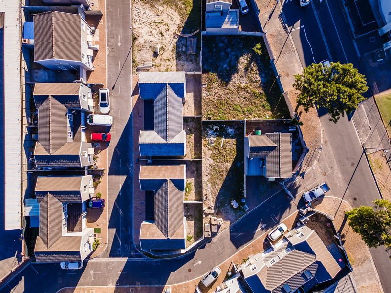 An aerial view of a residential housing complex showing the layout of multiple units, tiled roofs, and surrounding paved access roads.