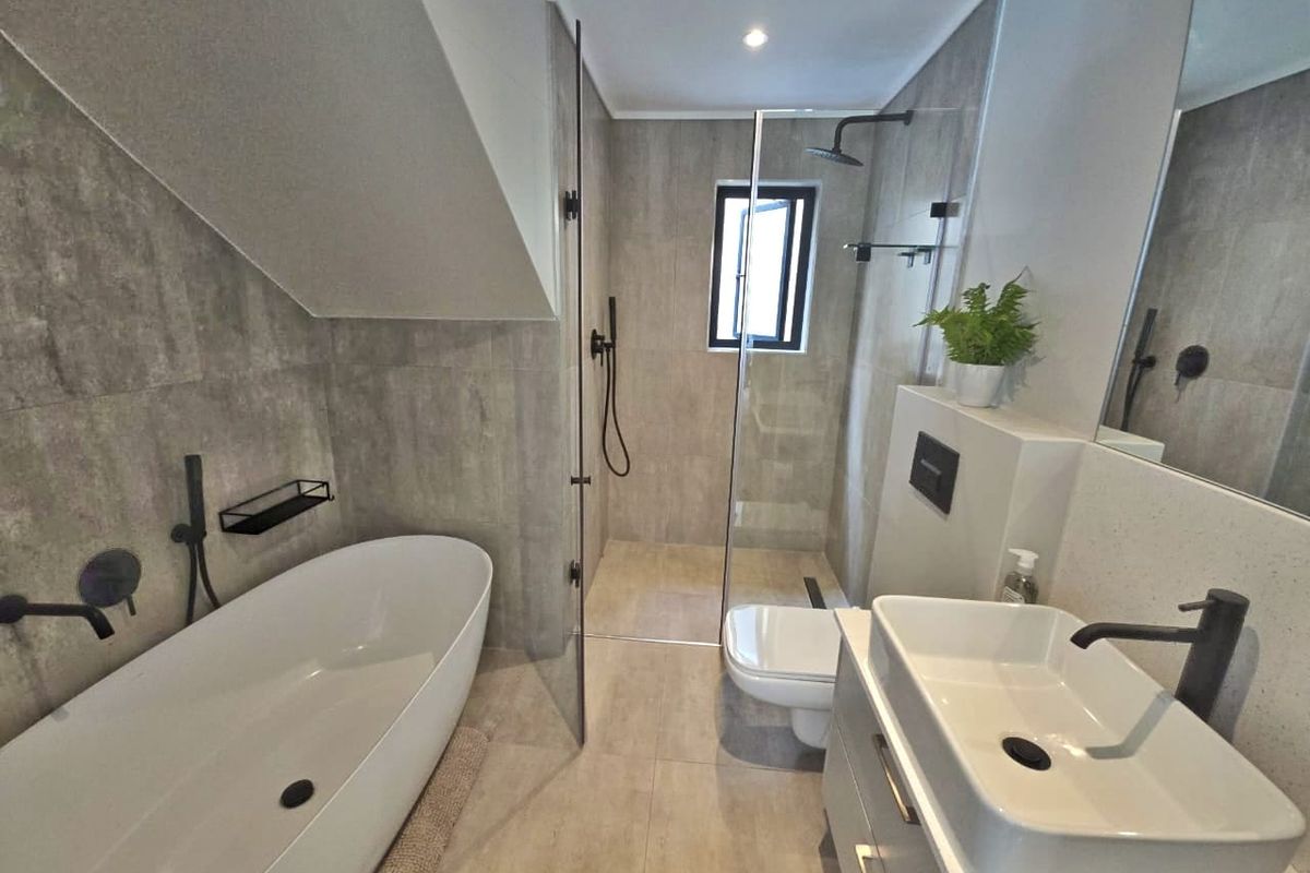 Modern bathroom featuring a freestanding bathtub, walk-in shower with glass screen, wall-mounted toilet, and a sleek vessel sink vanity with contemporary black matte fixtures.