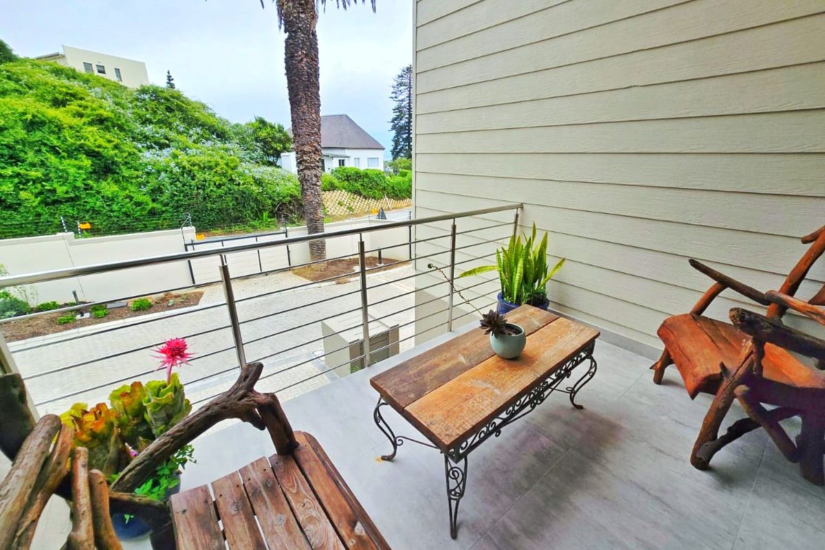 A covered balcony featuring modern tiled flooring and a stainless steel balustrade, offering an elevated view of the surrounding neighborhood.