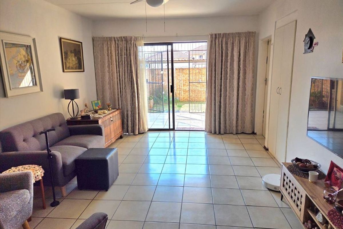 A bright living room featuring tiled flooring, a ceiling fan, and a sliding glass door providing direct access to the rear patio area.