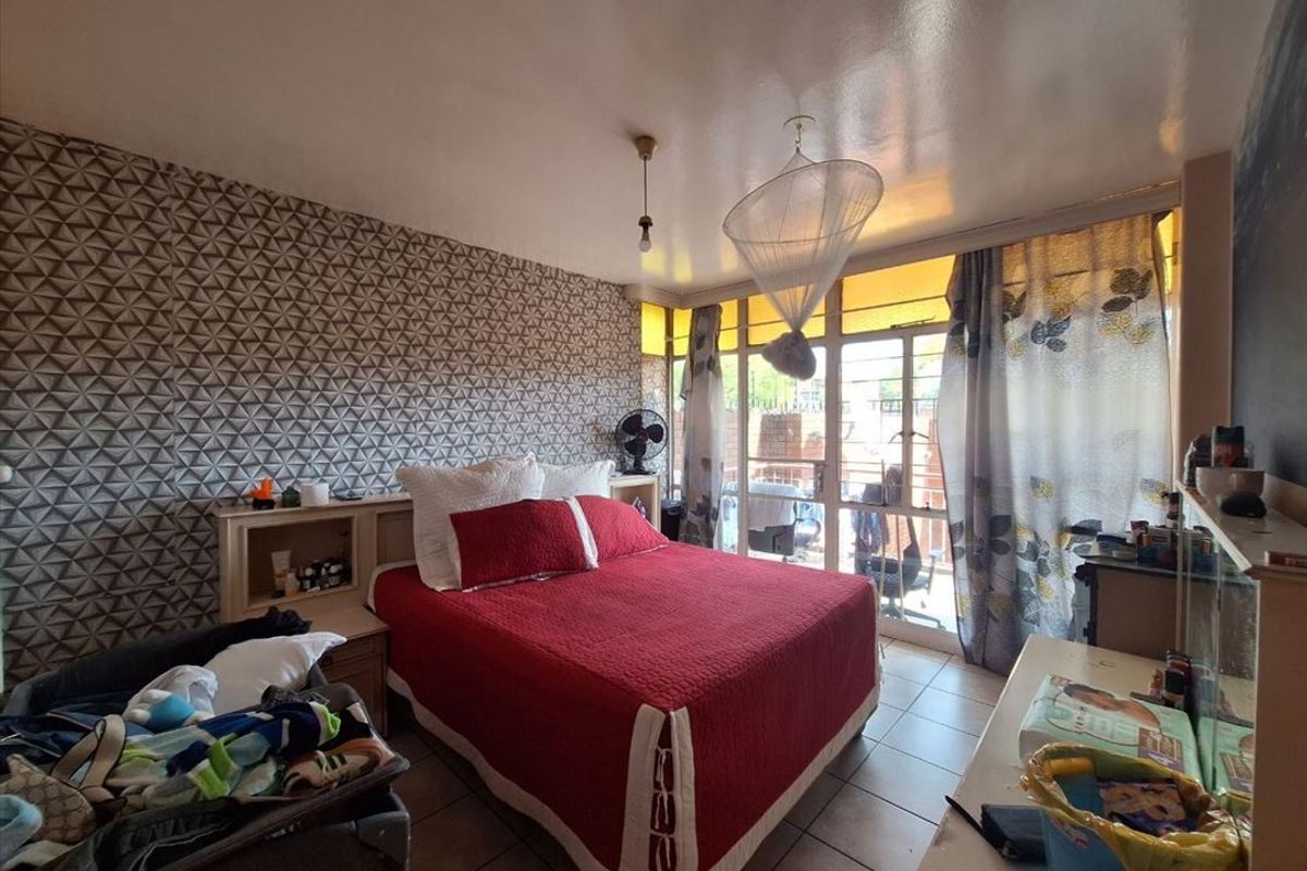 A bedroom featuring tiled flooring, a built-in headboard, and a sliding glass door providing access to an outdoor area.
