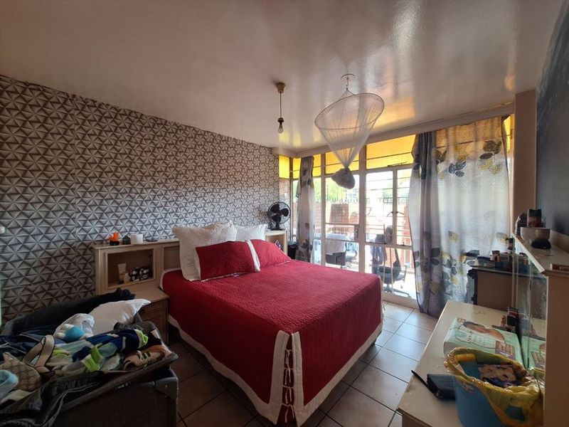 A bedroom featuring tiled flooring, a built-in headboard, and a sliding glass door providing access to an outdoor area.
