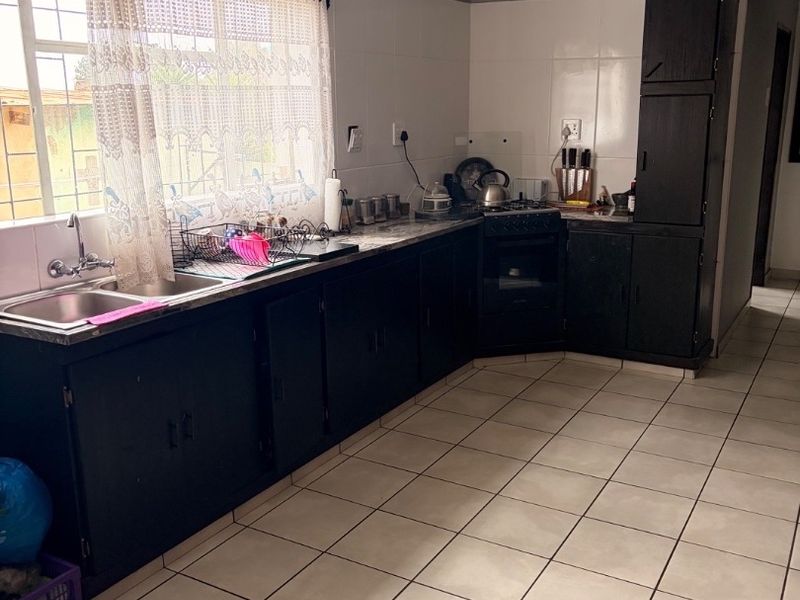 A functional kitchen featuring dark built-in cabinetry, tiled flooring, a double sink, and a built-in oven with hob.