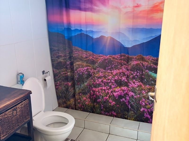 A functional bathroom featuring tiled flooring, wall tiling, and a shower area with a curtain.