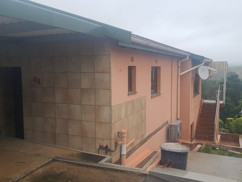 Front exterior view of the townhouse featuring a carport, tiled facade, and external staircase leading to the upper level.