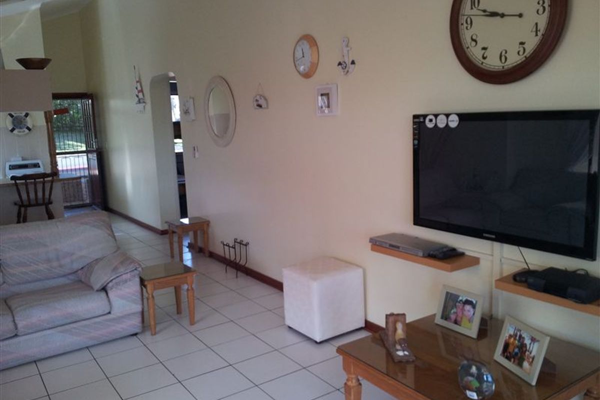 A living room featuring tiled flooring, a vaulted ceiling, and an archway leading to an adjacent space.