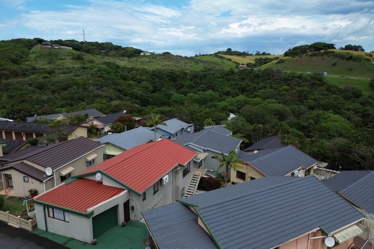 Aerial view of a residential townhouse complex featuring various roof styles and surrounding natural landscape.