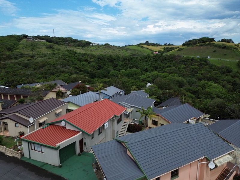 Aerial view of a residential townhouse complex featuring various roof styles and surrounding natural landscape.