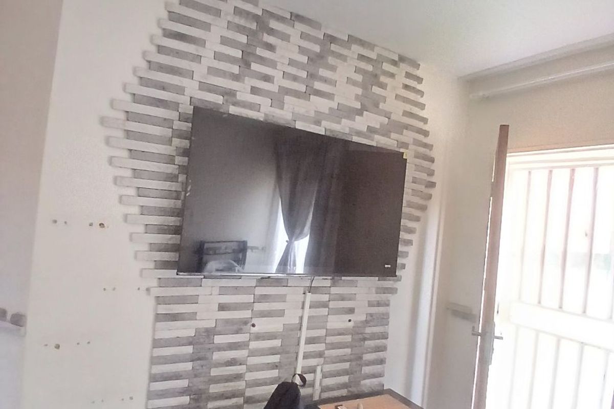 Living room area featuring a decorative stone-clad feature wall and a security gate entrance.