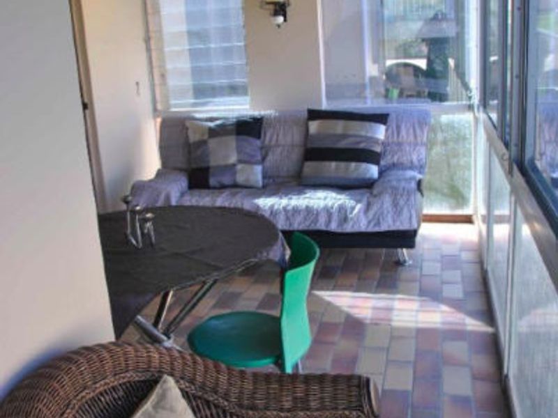 An enclosed patio area featuring tiled flooring and large glass windows, providing a versatile space for relaxation or outdoor dining.
