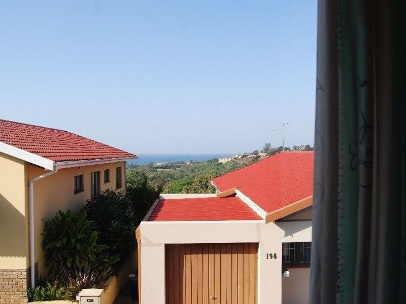 An elevated view overlooking neighbouring townhouse rooftops with a distant sea horizon visible in the background.