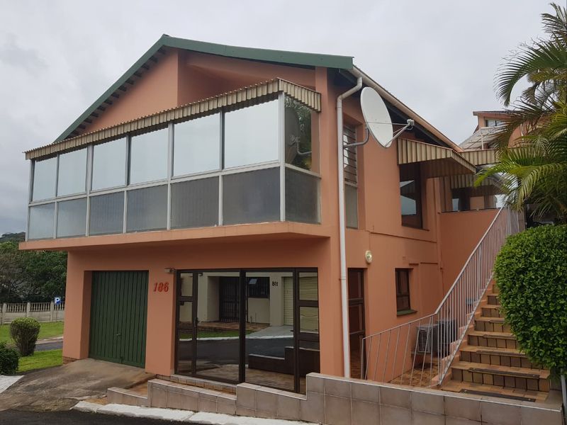 Front elevation of a two-story townhouse featuring an enclosed upper balcony, ground-level garage, and external staircase access.