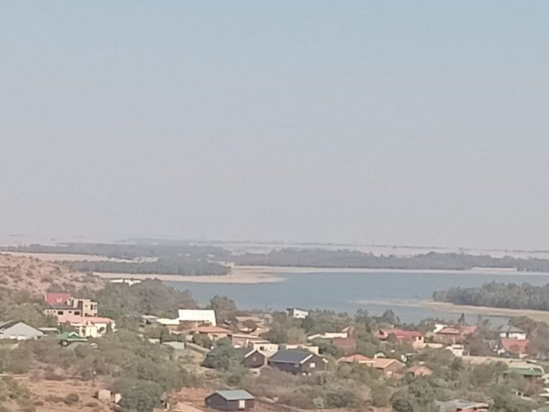 A wide-angle view of the surrounding landscape, featuring natural terrain and a distant water body.