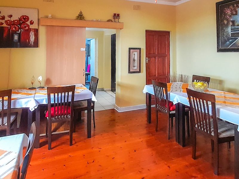 Spacious dining area featuring warm hardwood flooring and access to adjacent rooms through a sliding door and a traditional timber door.