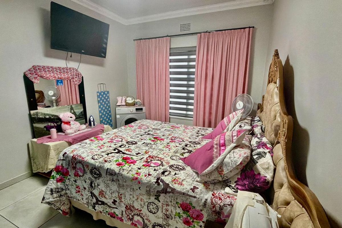 A bedroom featuring tiled flooring, neutral wall finishes, and a window with fitted blinds.