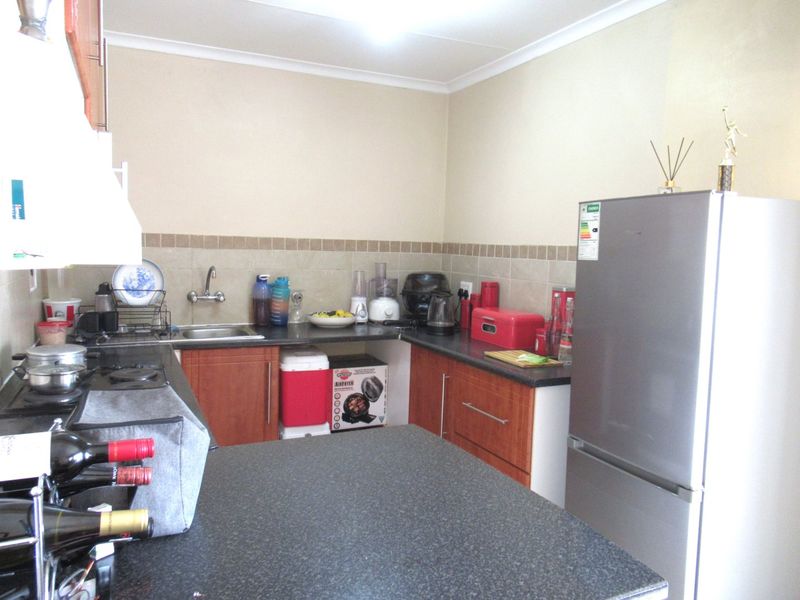 A functional kitchen featuring laminate cabinetry, granite countertops, a tiled backsplash, and a built-in hob, offering a practical layout for daily meal preparation.