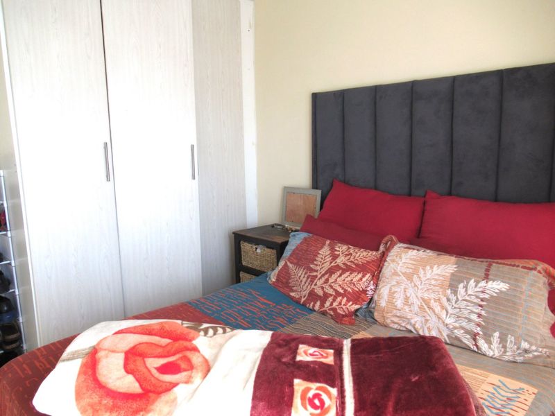 A bedroom featuring built-in cupboards with light wood-grain finish, providing functional storage space.