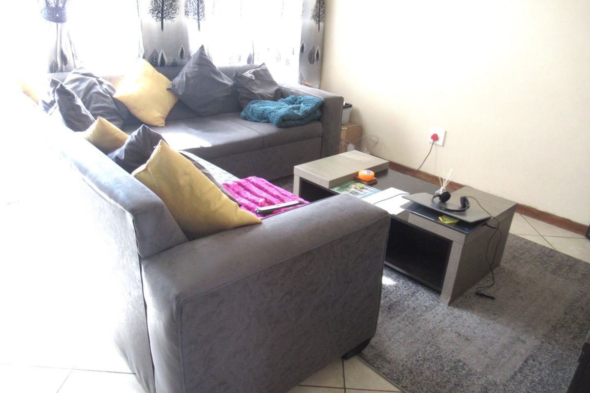 A living room area featuring tiled flooring and a neutral wall finish, providing a functional space for relaxation.