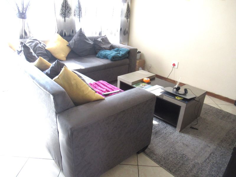 A living room area featuring tiled flooring and a neutral wall finish, providing a functional space for relaxation.
