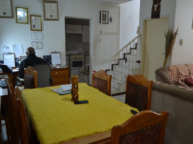 Open plan living and dining area featuring tiled floors, a staircase with a security gate, and a view into the adjacent kitchen space.