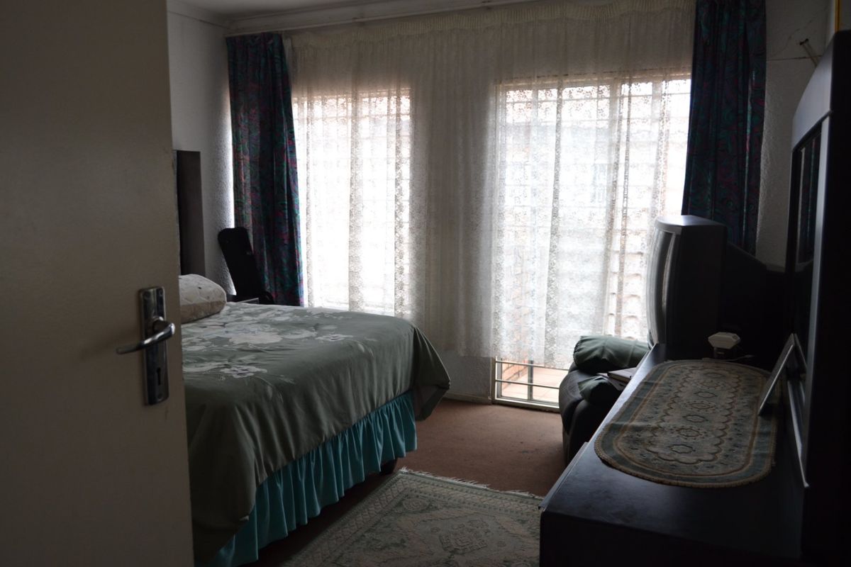 A bedroom featuring natural light through a sliding glass door with security bars, providing access to an outdoor area.