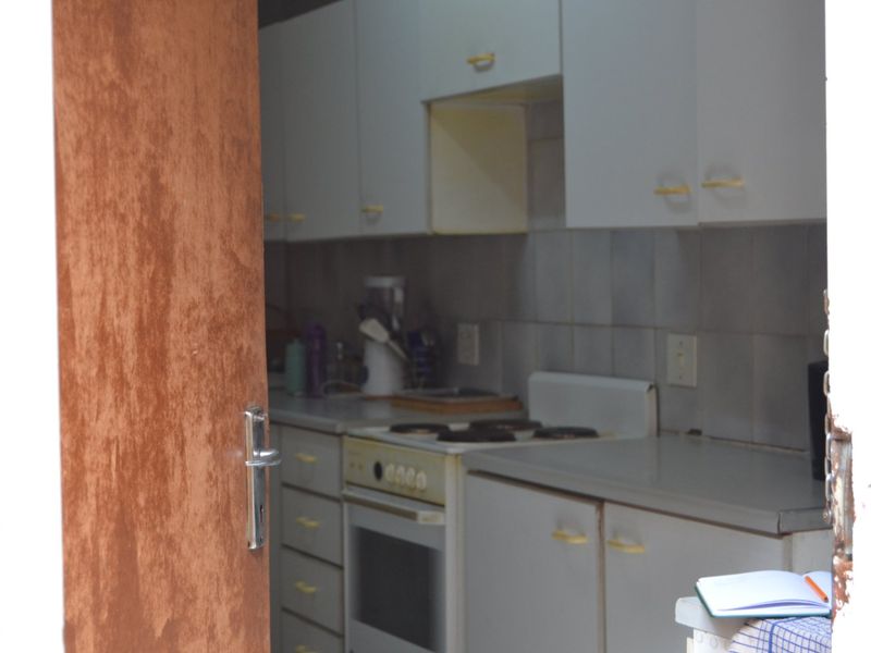 A compact kitchen featuring built-in cabinetry, an electric stove, and an oven, currently showing signs of age and wear.