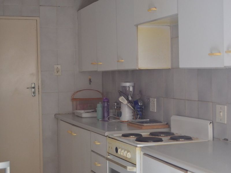 A functional kitchen featuring white built-in cabinetry, a tiled backsplash, and a standard electric stove and oven unit.