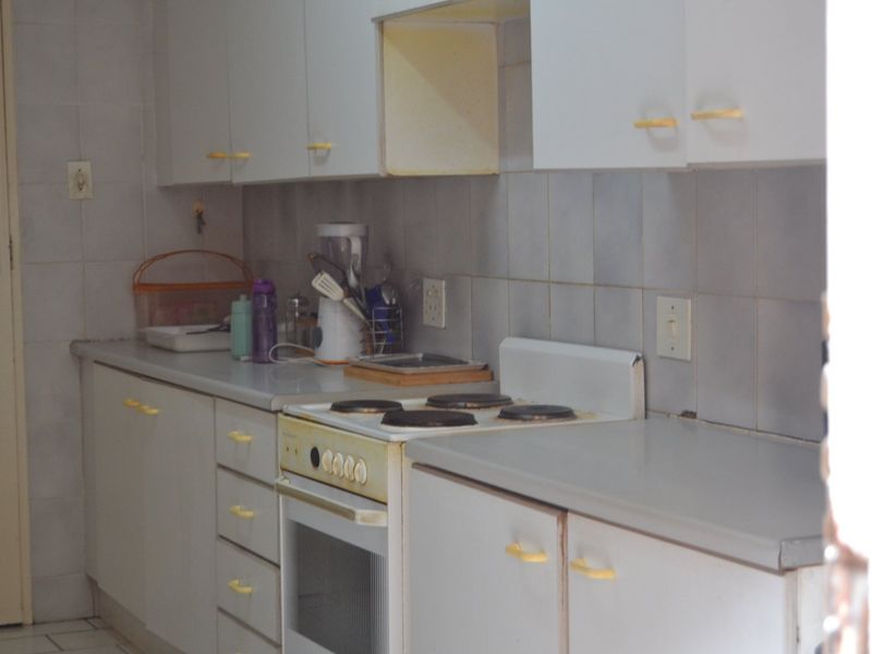 A functional kitchen featuring built-in cabinetry, tiled backsplash, and an integrated electric stove and oven, offering a dated but practical layout.