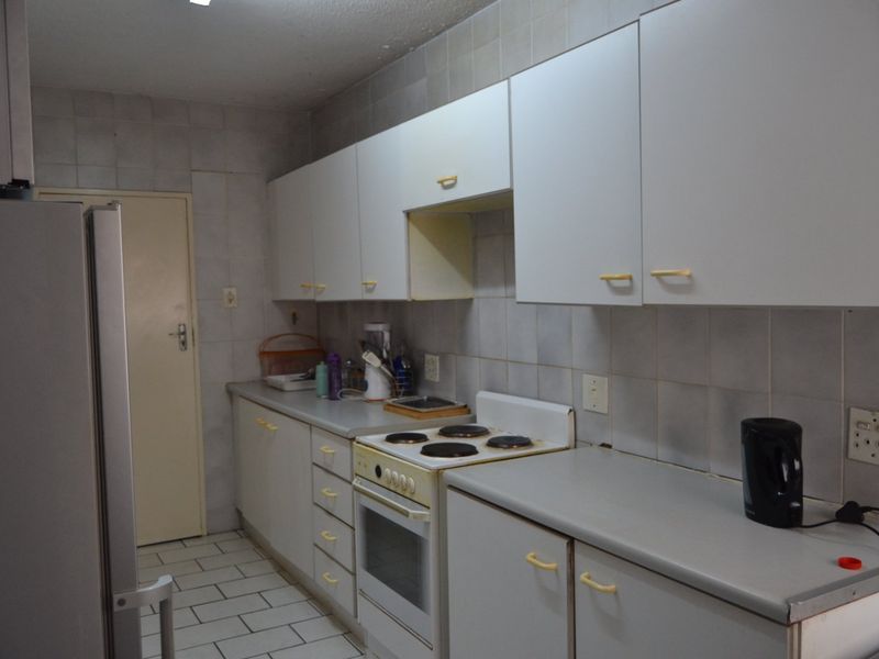 A functional kitchen featuring white built-in cabinetry, laminate countertops, an electric stove, and tiled backsplash and flooring.