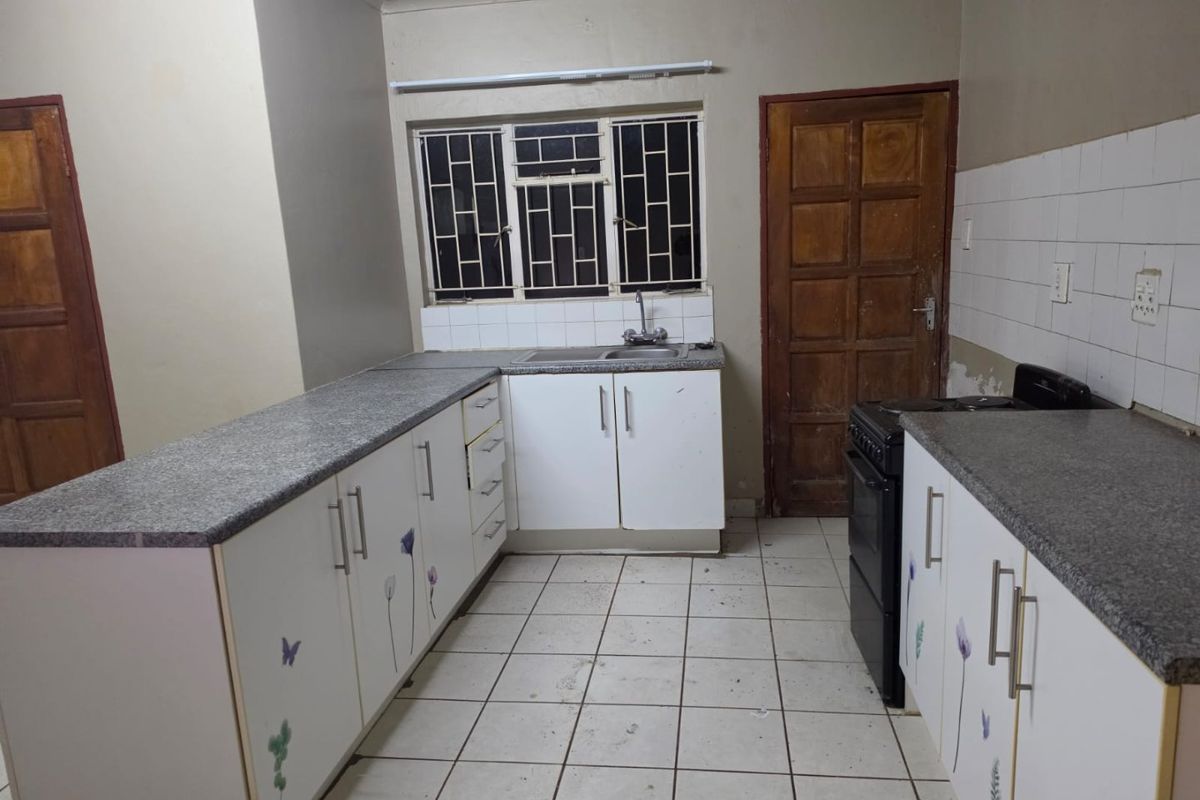 A functional kitchen featuring granite countertops, white cabinetry, tiled flooring, and a tiled backsplash, offering a blank canvas for potential modern updates.