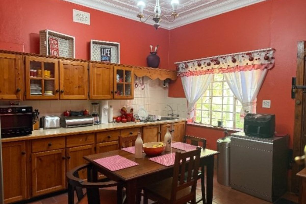 A traditional kitchen featuring timber cabinetry, tiled splashbacks, and an ornate plaster ceiling, offering a dated aesthetic with potential for modern renovation.