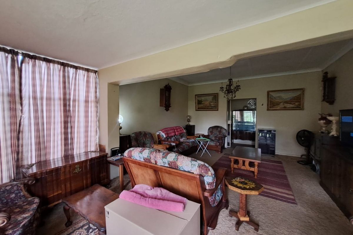 Spacious living area featuring coved ceilings and carpeted flooring, offering a traditional layout with potential for modernization.