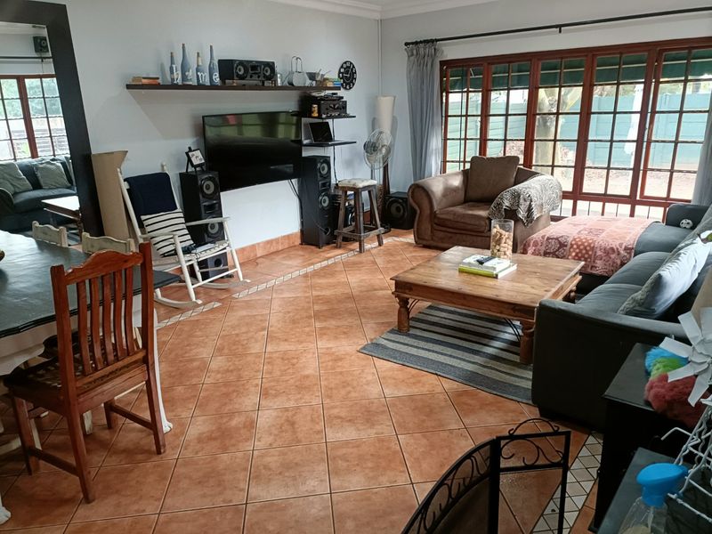 Spacious open-plan living and dining area featuring terracotta floor tiles and large timber-framed glass doors providing access to the exterior.