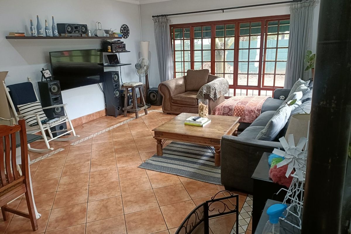 Spacious living room featuring terracotta floor tiles, coving, and large wooden-framed glass doors providing natural light and access to the outdoor area.