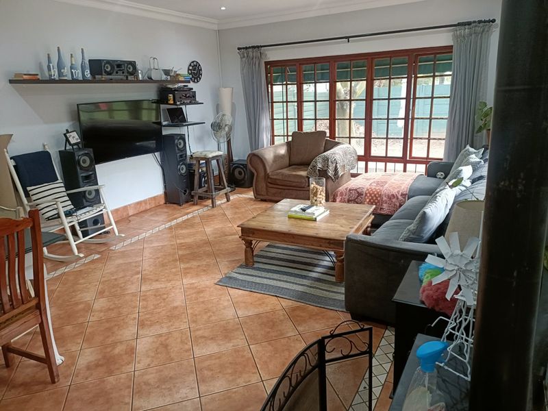 Spacious living room featuring terracotta floor tiles, coving, and large wooden-framed glass doors providing natural light and access to the outdoor area.