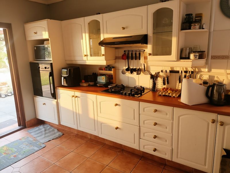 A functional kitchen featuring white cabinetry, a gas hob, built-in oven, and tiled flooring with direct access to the outdoor patio area.