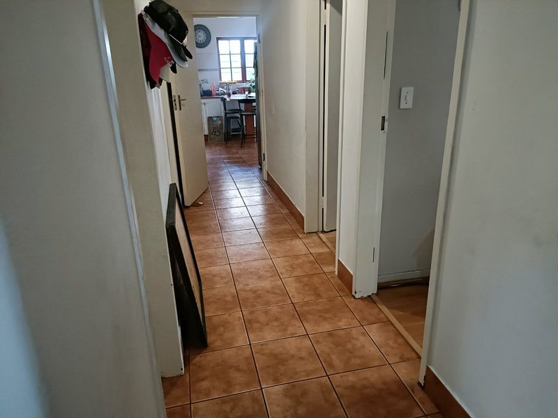 A functional hallway featuring tiled flooring and access to multiple rooms, including a view through to the kitchen area.