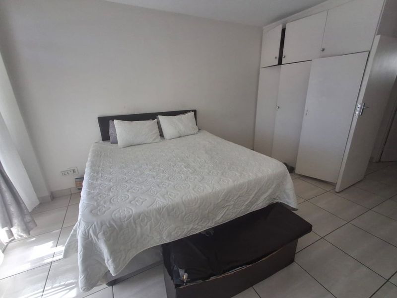 A bedroom featuring tiled flooring and built-in cupboards, providing functional storage space.