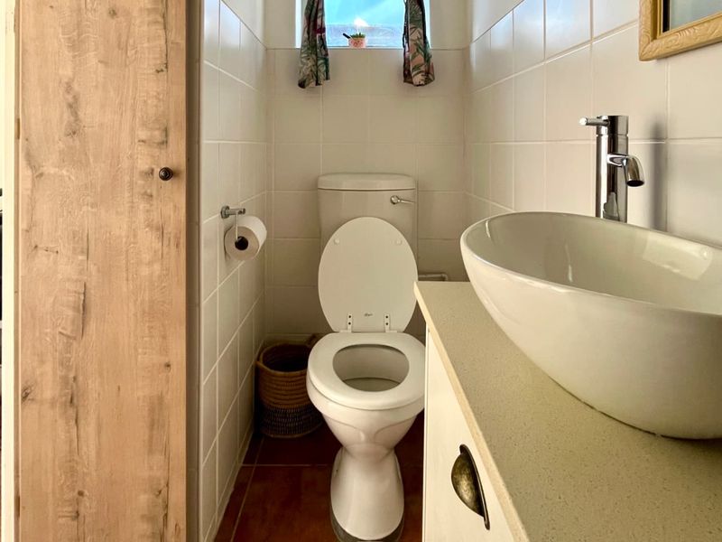 A compact bathroom featuring a white toilet, a modern vessel sink mounted on a vanity cabinet, and tiled wall finishes.
