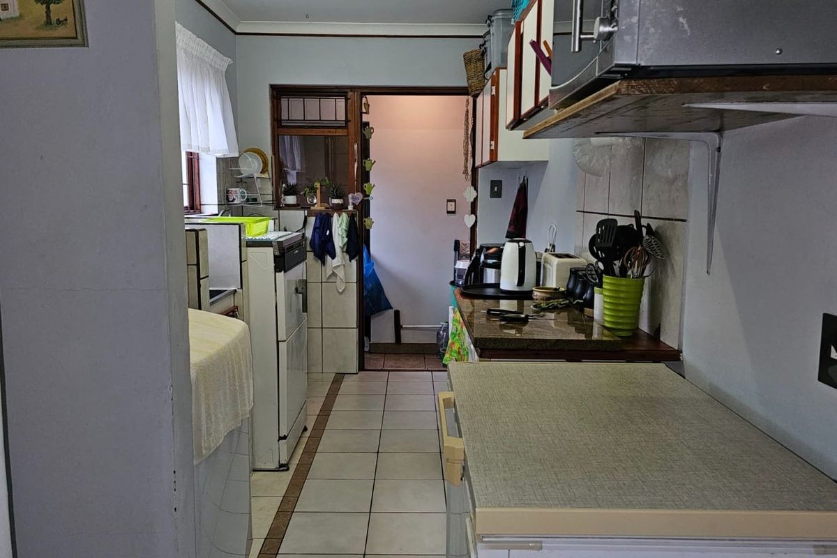A functional kitchen space featuring tiled flooring, laminate countertops, and built-in cabinetry, offering potential for modernization and aesthetic updates.