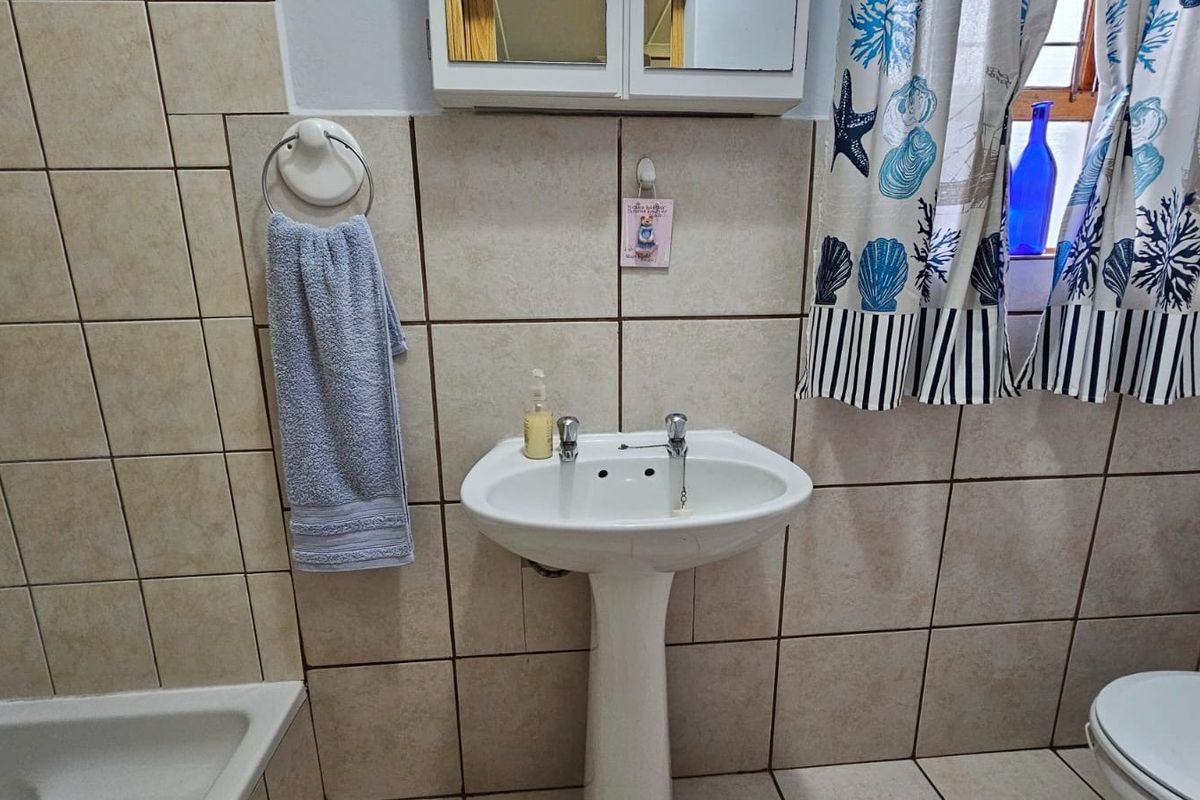 A functional bathroom featuring a pedestal basin, ceramic wall and floor tiling, and a built-in medicine cabinet.