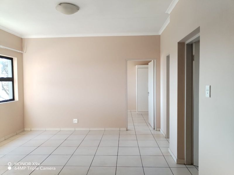 A bright, empty living area featuring neutral wall tones, tiled flooring, and clean architectural lines, ready for personalization.