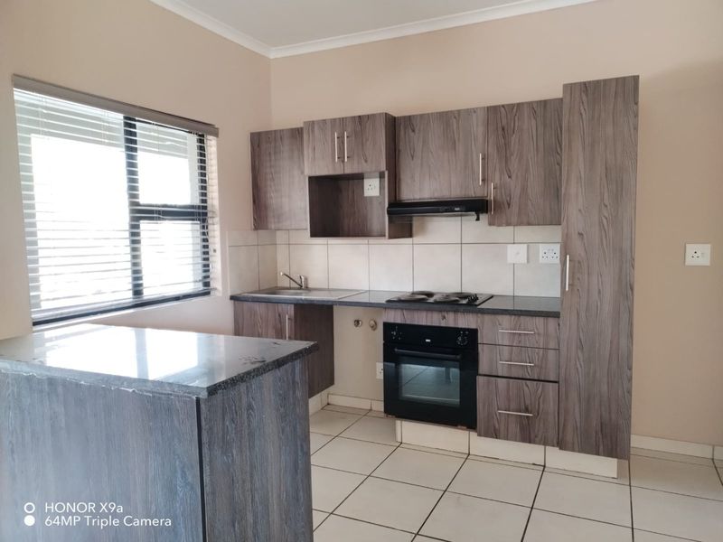 Modern kitchen featuring wood-grain cabinetry, granite countertops, built-in oven, electric hob, extractor fan, and tiled flooring.