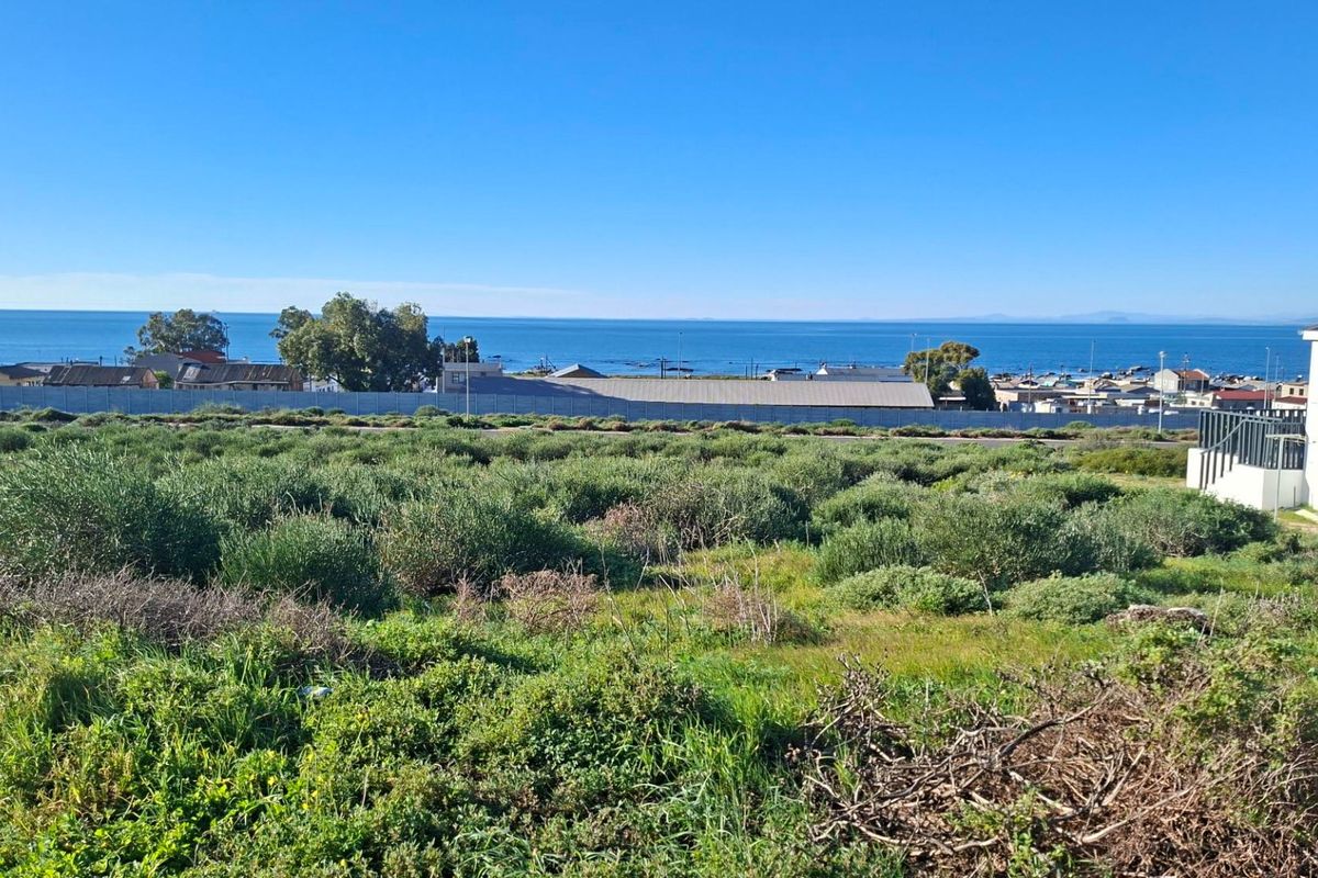 A scenic view overlooking a vacant residential plot with coastal and ocean vistas in the background.