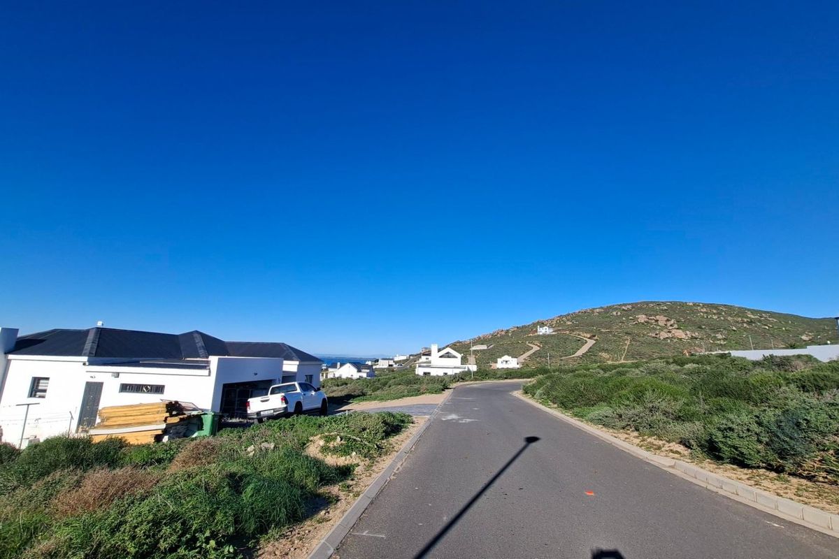 A clear street view showing the paved road and surrounding residential landscape in a coastal development area.