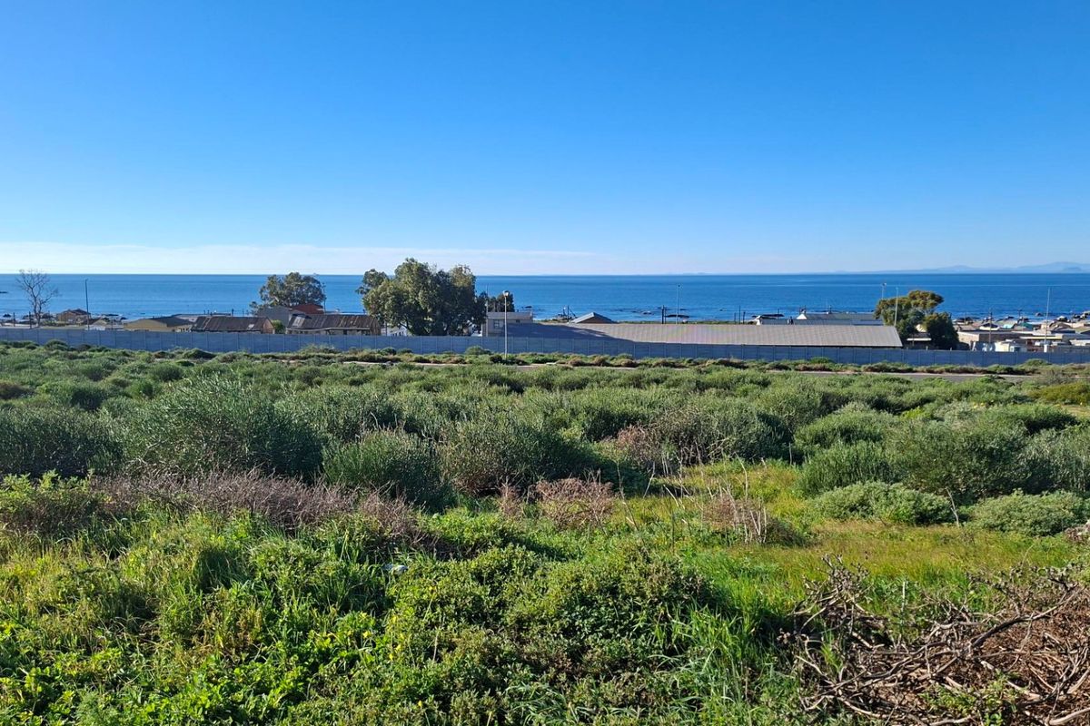 A scenic view overlooking a vacant residential plot with expansive ocean vistas in the background.