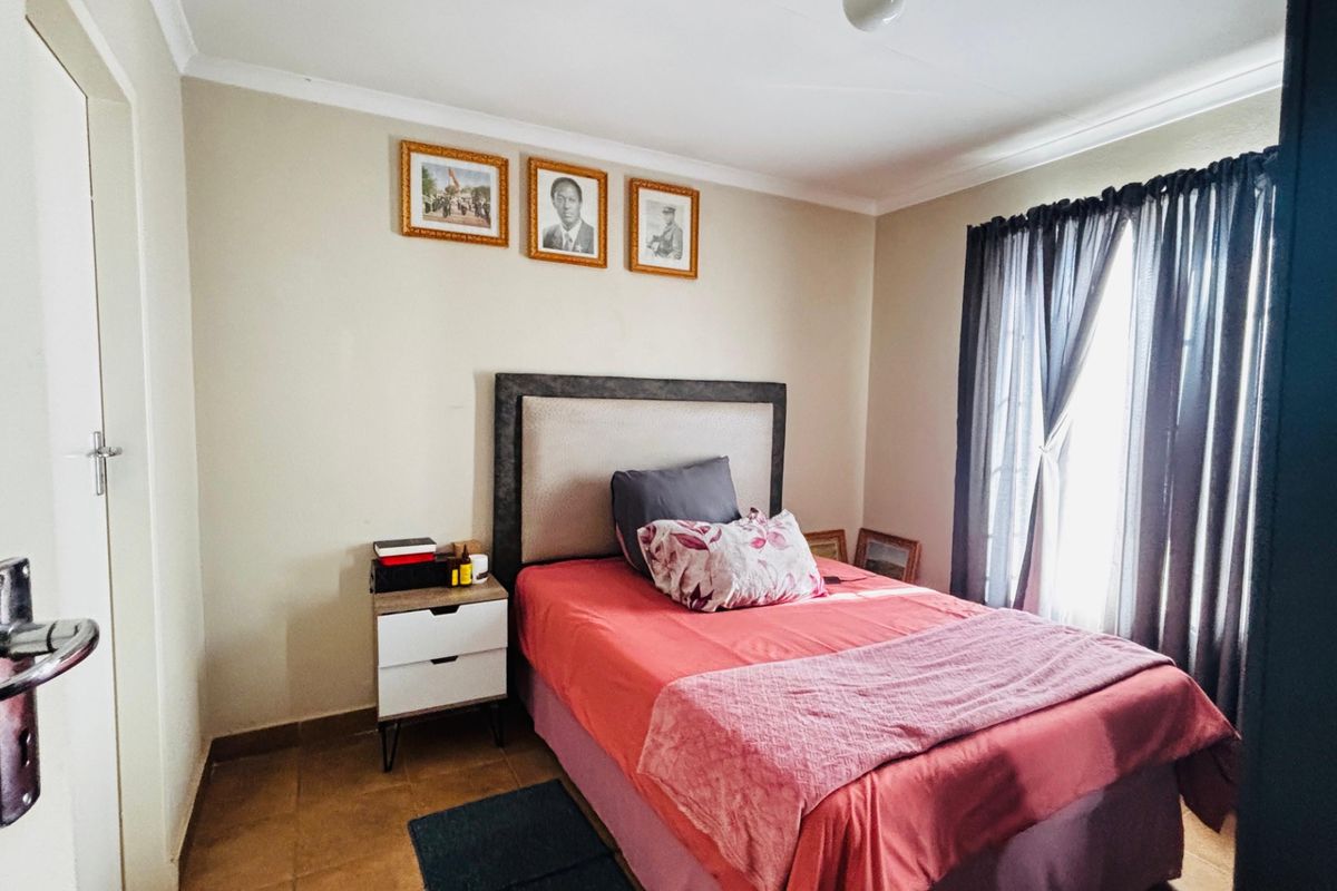 A functional bedroom featuring tiled flooring, neutral wall finishes, and cove cornicing, providing a comfortable and well-lit sleeping space.