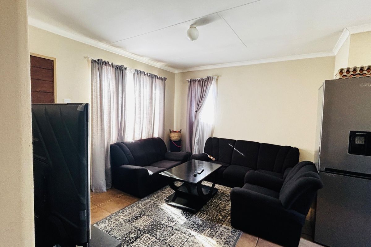 A living room featuring tiled flooring and coved ceilings, providing a functional space with natural light from the windows.