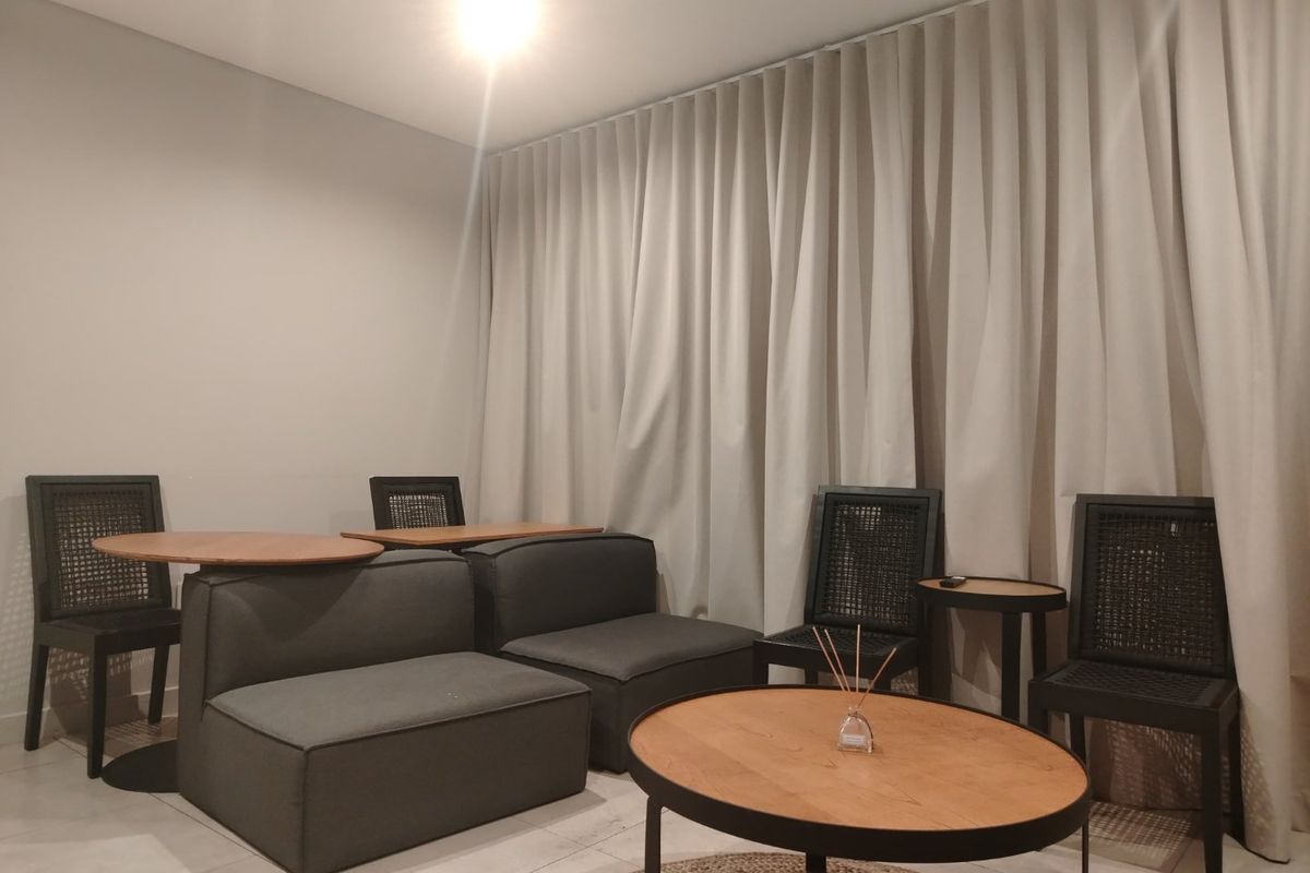 A modern living area featuring neutral-toned full-length curtains and clean tiled flooring, creating a bright and contemporary atmosphere.